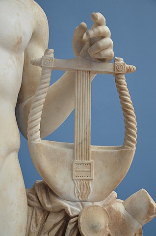 a cropped photo of a white marble statue of apollo, showing his hand resting on a lyre
