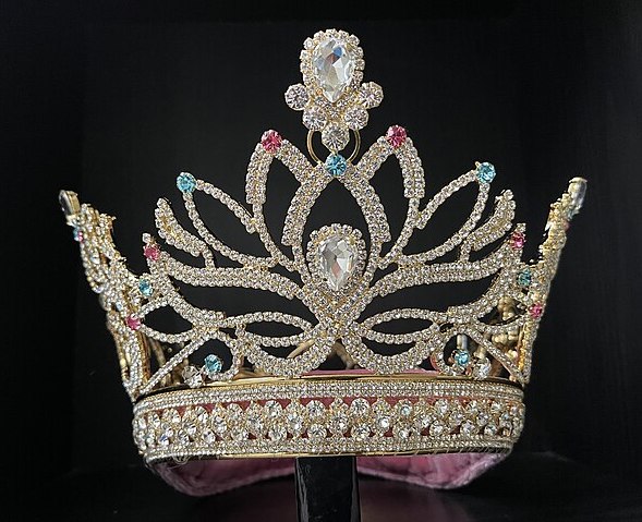 a pagent-style crown embedded with white, pale pink, and pale blue rhinestones