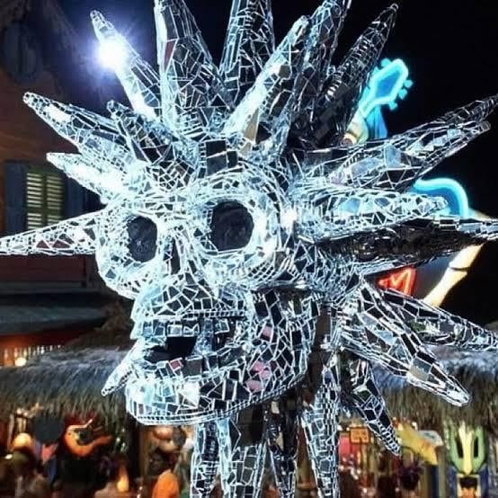 A decorative skull with large spikes that is covered in mirror glass like a disco ball